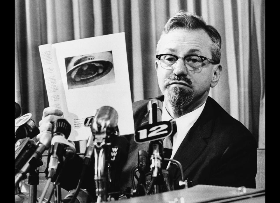 Northwestern University Astrophysicist, J. Allen Hynek, shown at a press conference, March 25, 1966, Detroit, Mi. A newsman handed this photo to Hynek and asked him if it was a flying saucer. Hynek described it as a chicken feeder and said that numerous sightings of recent unidentified flying objects in Michigan were probably the result of swamp gasses and not visitors from outer space. Hynek has studied and investigated UFOs for the past 15 years. (AP Photo/ Alvin Quinn)