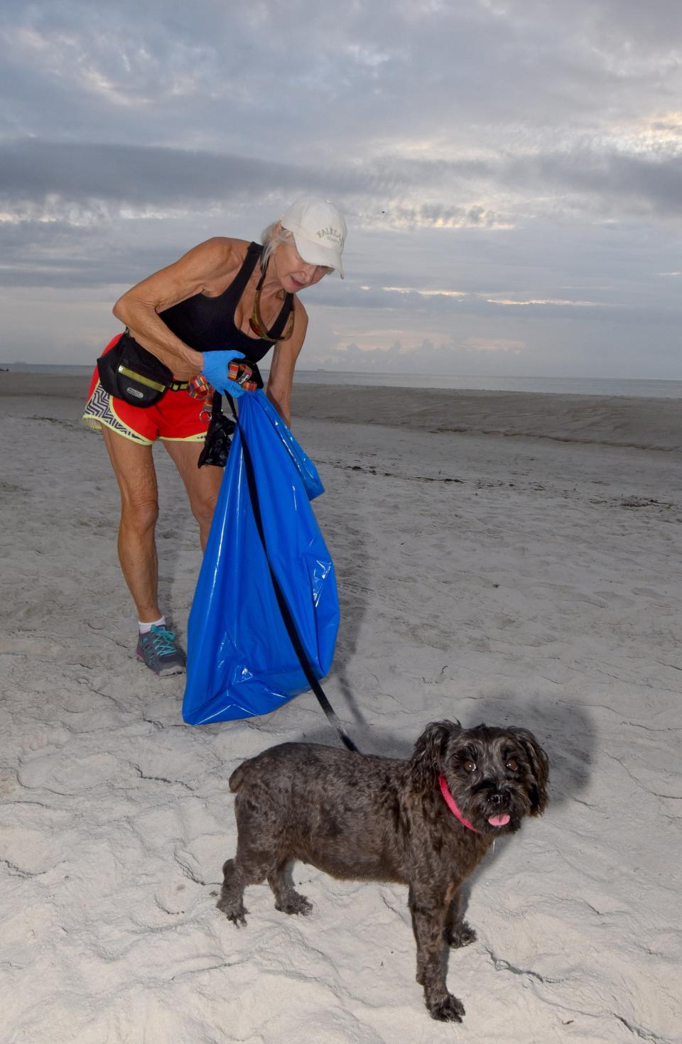 Joyce DeVane and her dog, Ava, pick up small bits of trash from the sands of Neptune Beach on July 5, 2020.