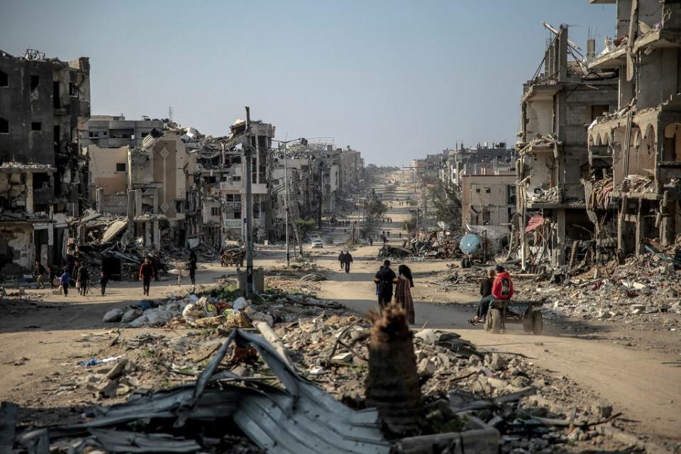 Palestinians walk past buildings destroyed during Israeli strikes in Beit Lahia in northern Gaza on Feb. 26 amid continuing battles between Israel and the Palestinian militant group Hamas.