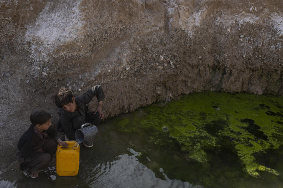 Two brothers fill canisters with water from a stagnant pool about 3 kilometers (2 miles) from their home in Kamar Kalagh village outside Herat, Afghanistan, Friday, Nov. 26, 2021. Afghanistan’s drought, its worst in decades, is now entering its second year, exacerbated by climate change. (AP Photo/Petros Giannakouris)