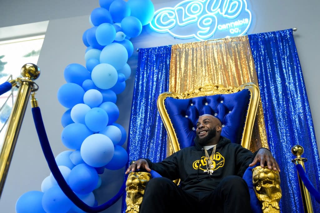 Cloud 9 Cannabis CEO and co-owner Sam Ward Jr. smiles while posing for a photo in a throne photo-op for customers, Saturday, April 13, 2024, in Arlington, Wash. (AP Photo/Lindsey Wasson)