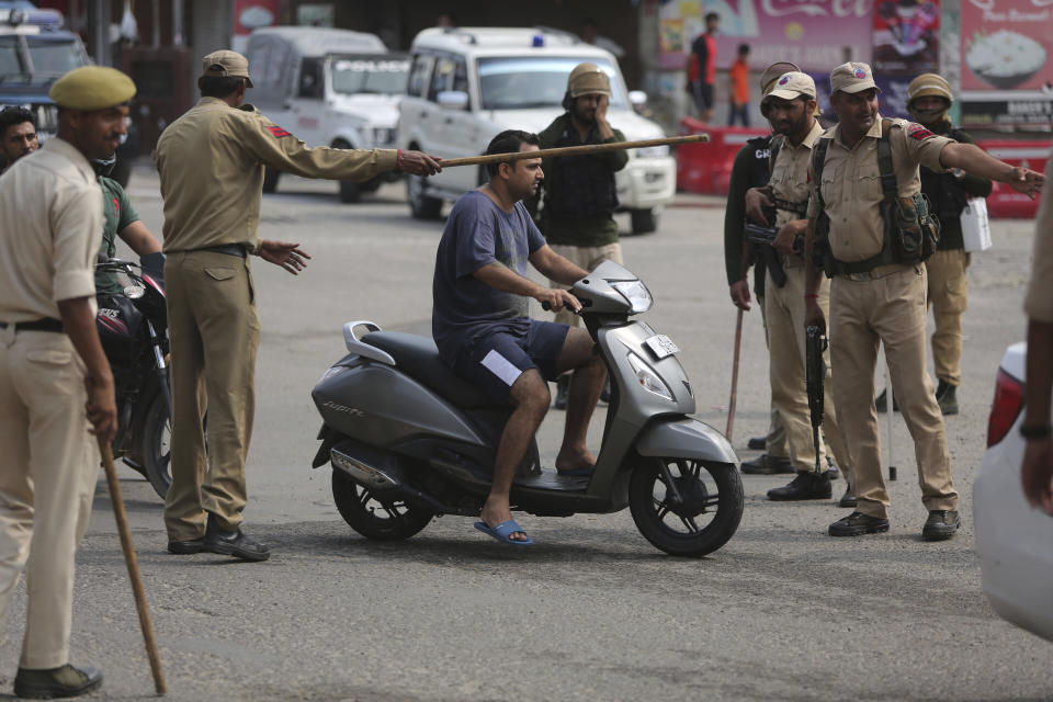 Indian police check the identity of commuters in Jammu, India, Tuesday, Aug.6, 2019. India's lower house of Parliament was set to ratify a bill Tuesday that would downgrade the governance of India-administered, Muslim-majority Kashmir amid an indefinite security lockdown in the disputed Himalayan region. The Hindu nationalist-led government of Prime Minister Narendra Modi moved the "Jammu and Kashmir Reorganization Bill" for a vote by the Lok Sahba a day after the measure was introduced alongside a presidential order dissolving a constitutional provision that gave Kashmiris exclusive, hereditary rights. (AP Photo/Channi Anand)