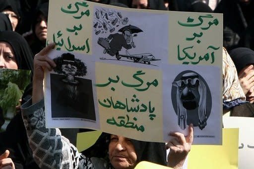 An Iranian woman holds a banner with cartoons depicting Libyan leader Moamer Kadhafi, ousted Egyptian president Hosni Mubarak and Saudi King Abdullah bin Abdul Aziz during a protest in Tehran against the crackdown on pro-democracy protesters in Bahrainand the unrest in Libya