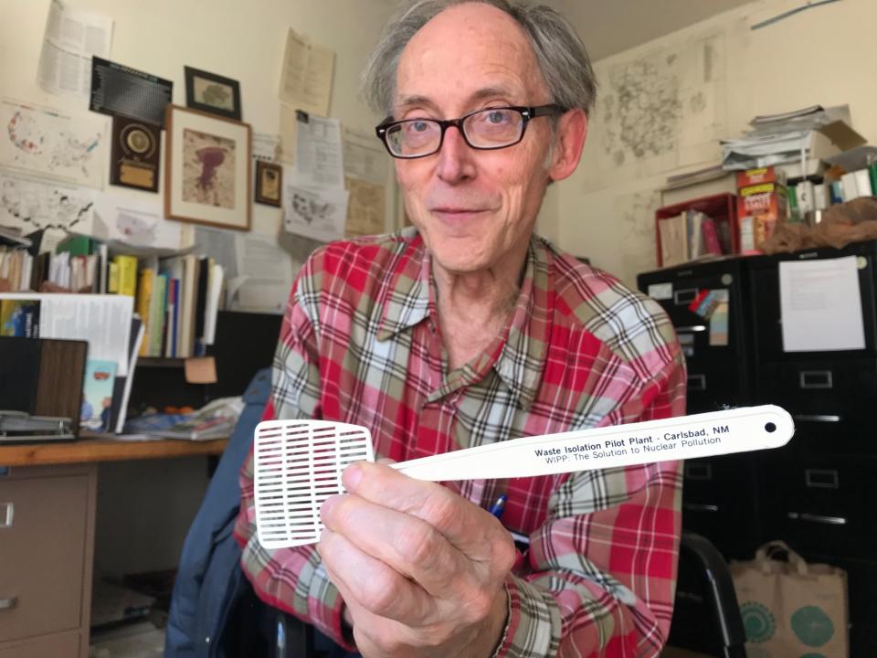 In this March 5, 2019 photo, Don Hancock with the Southwest Research and Information Center holds up a promotional flyswatter advertising the Waste Isolation Pilot Plant as the solution to nuclear pollution while in his office in Albuquerque, New Mexico. Hancock is among the watchdogs who have been monitoring the federal nuclear waste repository for decades. (AP Photo/Susan Montoya Bryan)