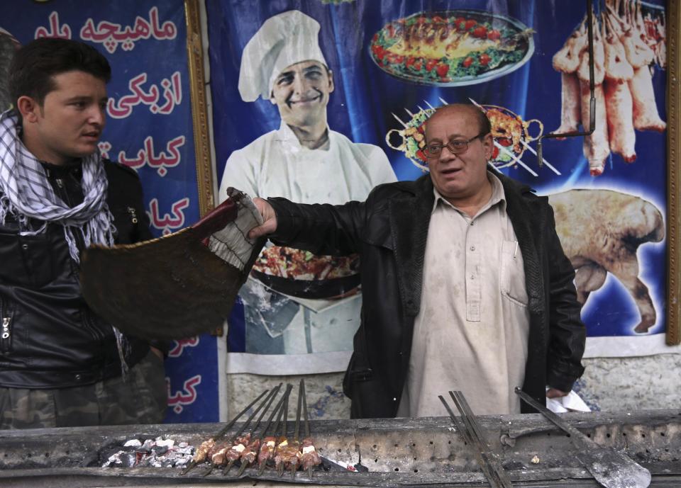 Zabulon Simantov, an Afghan Jew, fans kebabs being grilled for customers, at his cafe in Kabul