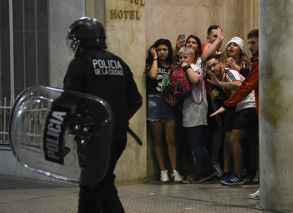 Un grupo de personas se resguarda durante los choques entre policías antimotines e hinchas tras los festejos en Buenos Aires por el título conquistado por River Plate en la final de la Copa Libertadores, el domingo 9 de diciembre de 2018. (AP Foto/Gustavo Garello)