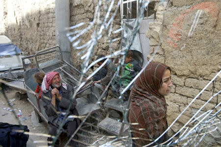 People are seen through a shattered glass in the besieged town of Douma, Eastern Ghouta, in Damascus, Syria March 19, 2018. REUTERS/Bassam Khabieh