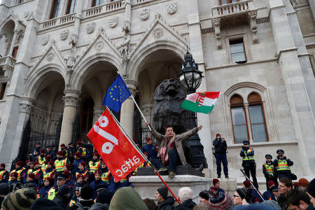 A woamn holds flags as trade union members and supporters protest against the government in front of the Parliament building in Budapest, Hungary, December 8, 2018. REUTERS/Bernadett Szabo