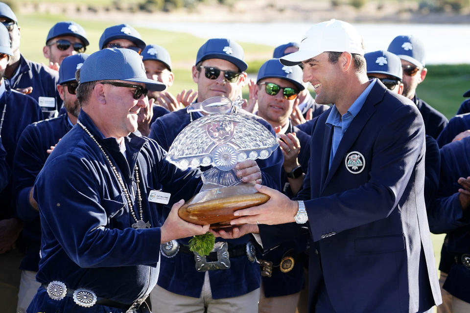 Scottie Scheffler, right, is presented the championship trophy by tournament chairman Pat Williams after the final round of the Phoenix Open golf tournament, Sunday, Feb. 12, 2023, in Scottsdale, Ariz. (AP Photo/Darryl Webb)