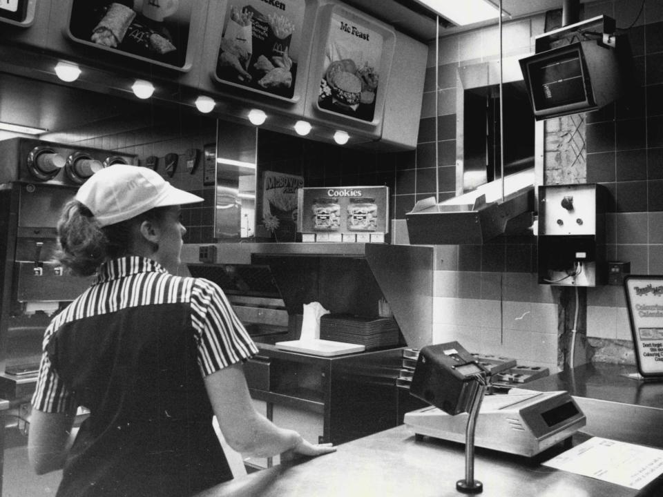 An employee puts orders onto a conveyer belt which delivers food to the drive-in section of the McDonalds restaurant in 1984.