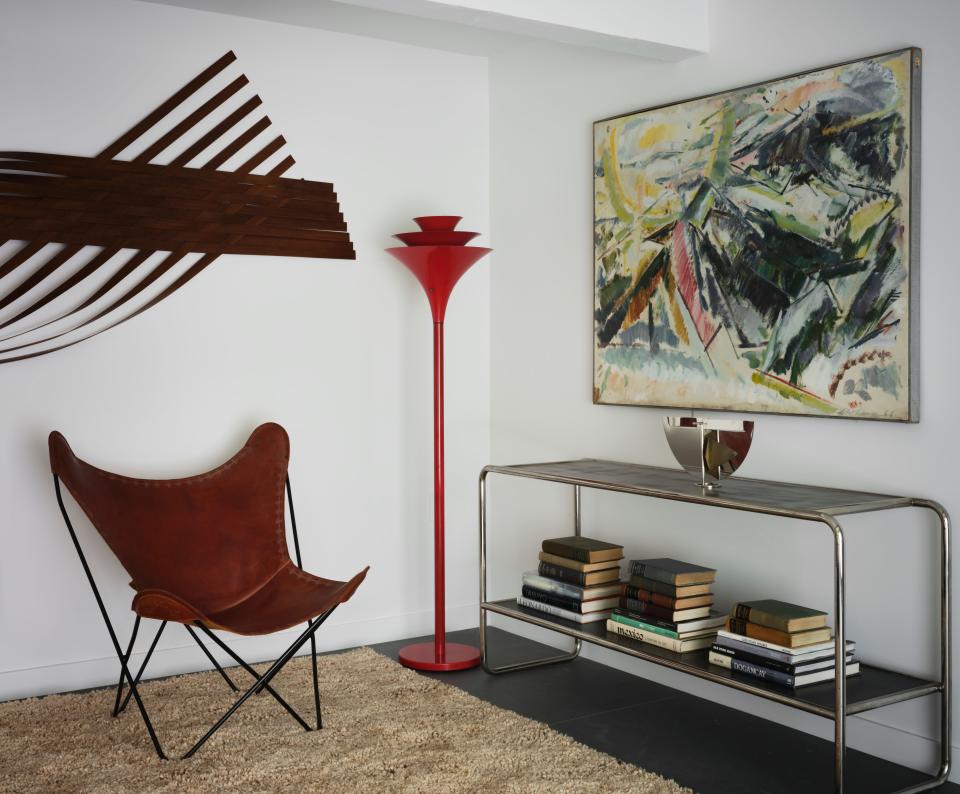 A butterfly chair designed by Jorge Ferrari Hardoy, Juan Kurchan, and Antonio Bonet for Knoll, circa 1938, sits next to a fire-engine red Torchiere lamp from the 1960s.