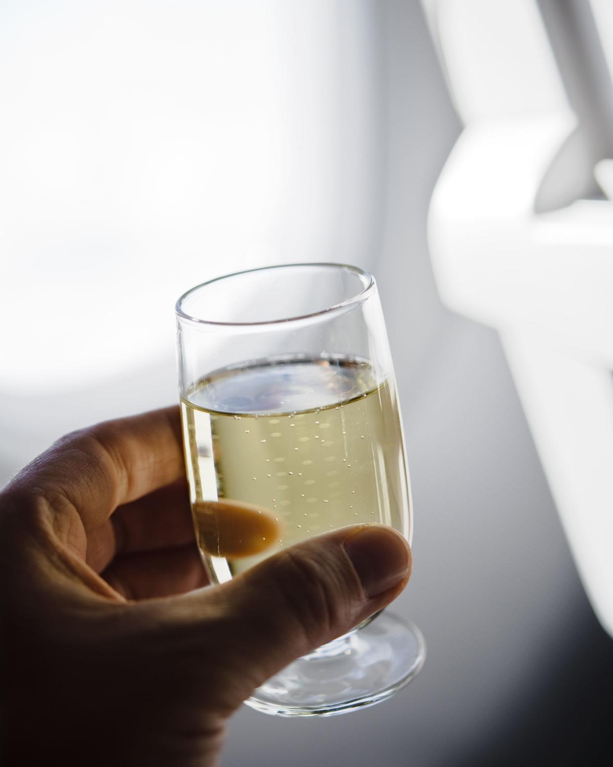 hand holding champagne glass in airplane, close-up