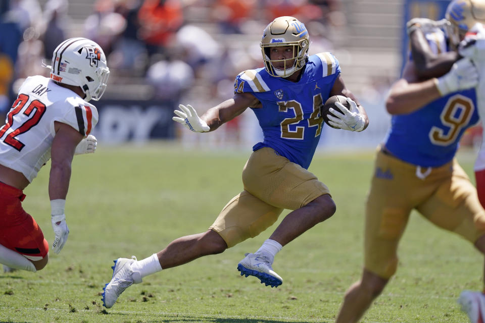 UCLA running back Zach Charbonnet, center, tries to avoid a tackle by Bowling Green safety Patrick Day, left, during the first half of an NCAA college football game Saturday, Sept. 3, 2022, in Pasadena, Calif. (AP Photo/Mark J. Terrill)