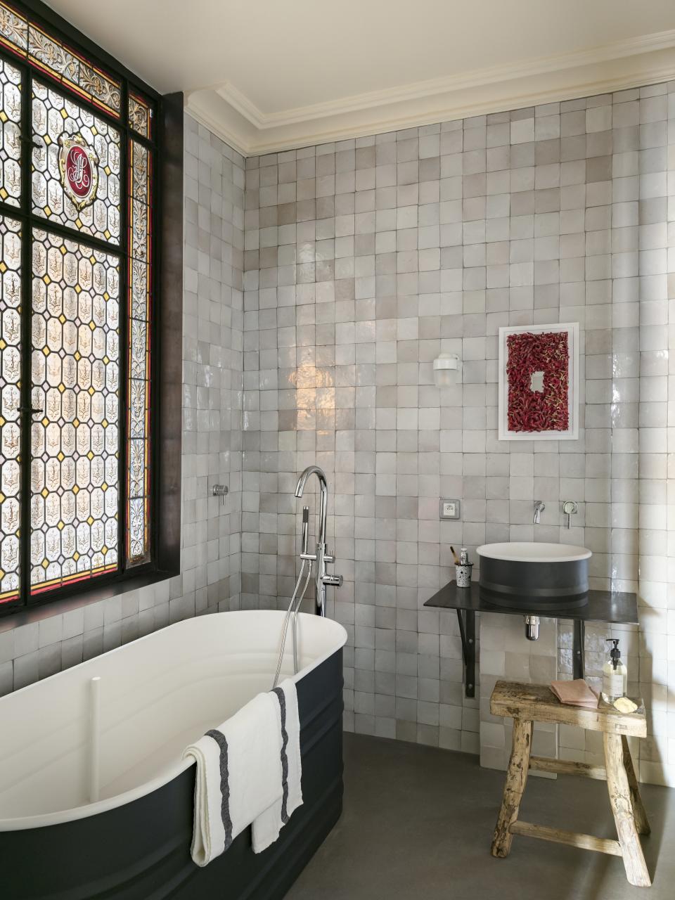 Tile and glasswork shine in the bathroom, which features bath linens and Meraki liquid soap from Merci. The bathtub and sink are by Patricia Urquiola for Agape.