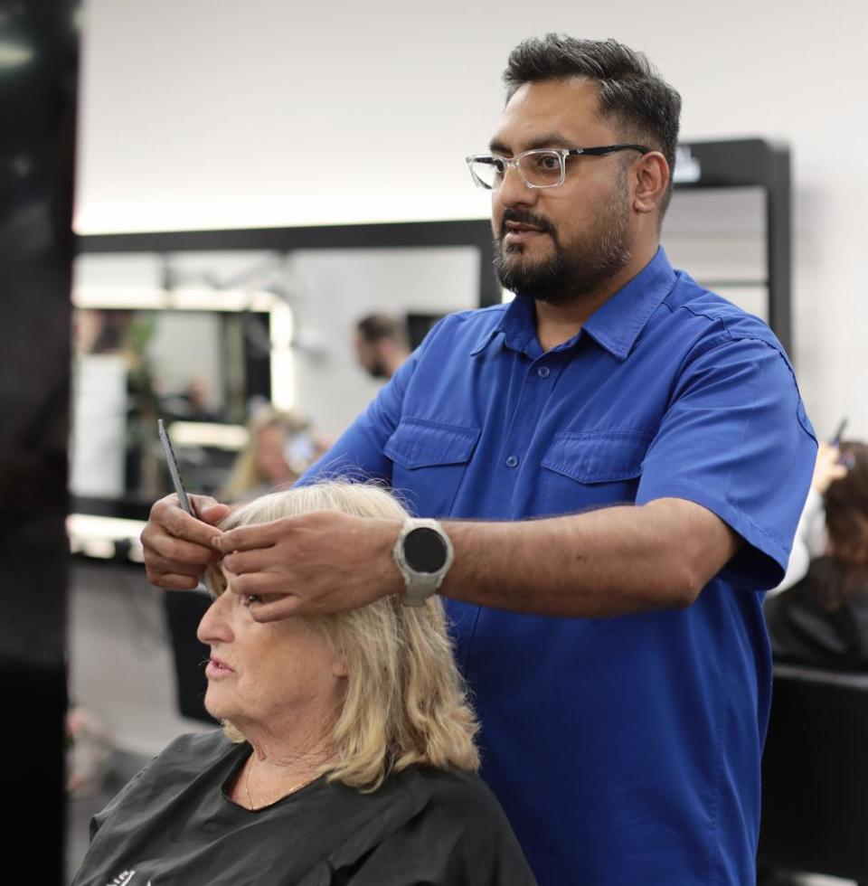 The hairdresser Chigz Hirani cuts a client’s hair