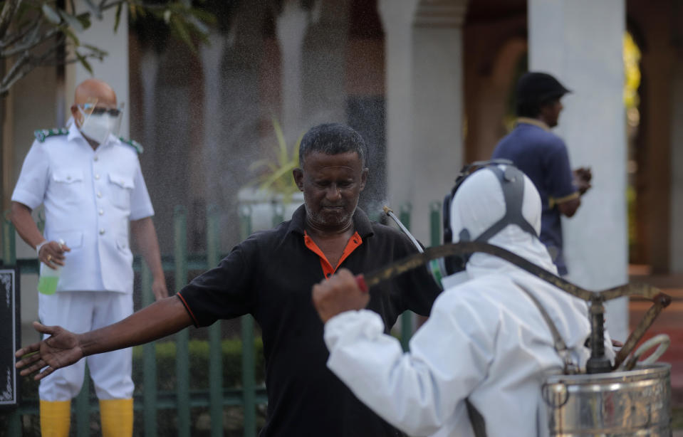 A Sri Lankan municipal health worker disinfects a colleague after the cremation of a COVID-19 victim at a cemetery in Colombo, Sri Lanka, Friday, Jan. 22, 2021. Sri Lanka on Friday approved the Oxford-AstraZeneca vaccine for COVID-19 amid warnings from doctors that front-line health workers should be quickly inoculated to stop the system from collapsing. (AP Photo/Eranga Jayawardena)