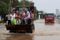 Rescuers evacuate people from a flooded area in Weihui in central China's Henan Province, Monday, July 26, 2021. Residents laid flowers on Tuesday at the entrance of a subway station where more than a dozen people died after a record-breaking downpour flooded large swaths of Henan province in central China. (Chinatopix via AP)