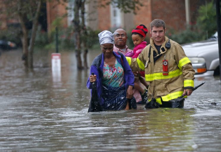 A member of the St. George Fire Department assists residents as they wade through floodwater at the Chateau Wein Apartments in Baton Rouge, La. (Photo: Gerald Herbert/AP)