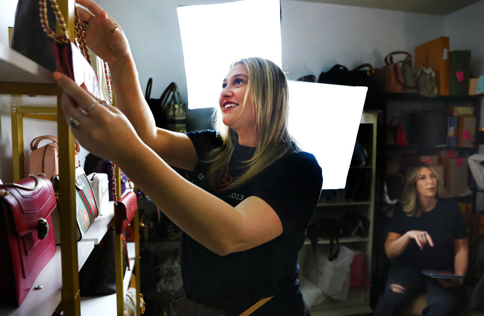 Samantha Mayer, left, and her mother Deborah Mayer prep handbags before selling live on TikTok, Wednesday, March 21, 2024, in Freehold, N.J. Deborah Mayer has sold new and pre-owned handbags and other designer goods out of her New Jersey home for 16 years. Early last year, TikTok recruited her business for the live component of TikTok Shop. (AP Photo/Noah K. Murray)