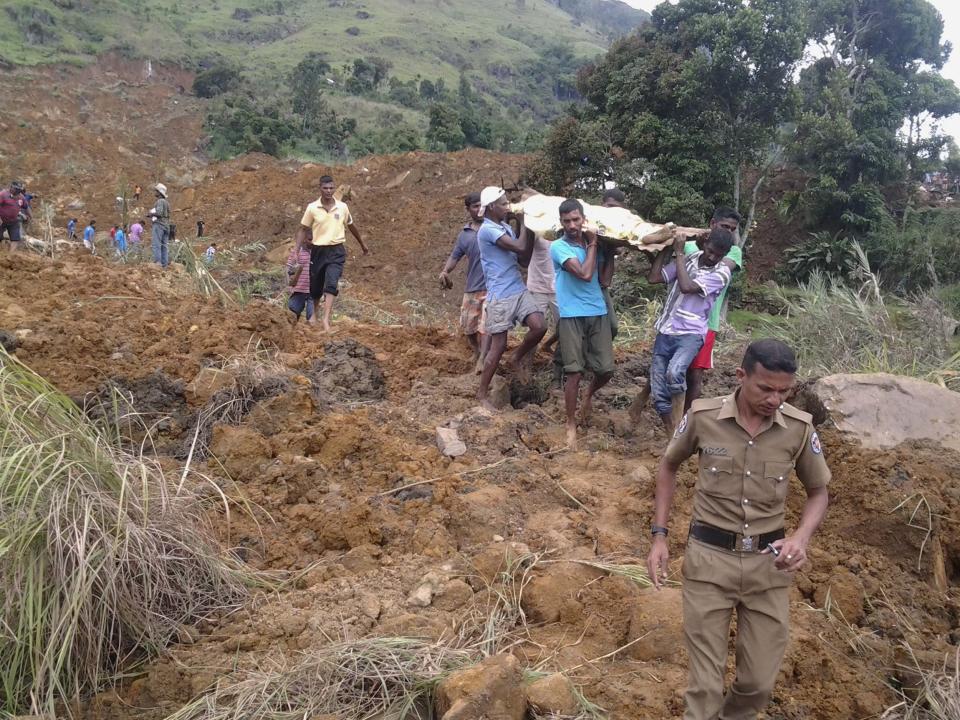 Villagers carry a dead body after a landslide at the Koslanda tea plantation in Badulla