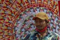 An anti-coup protester stands next to images of deposed Myanmar leader Aung San Suu Kyi during a street march in Mandalay, Myanmar, Thursday, Feb. 25, 2021.Social media giant Facebook announced Thursday it was banning all accounts linked to Myanmar's military as well as ads from military-controlled companies in the wake of the army's seizure of power on Feb. 1. (AP Photo)