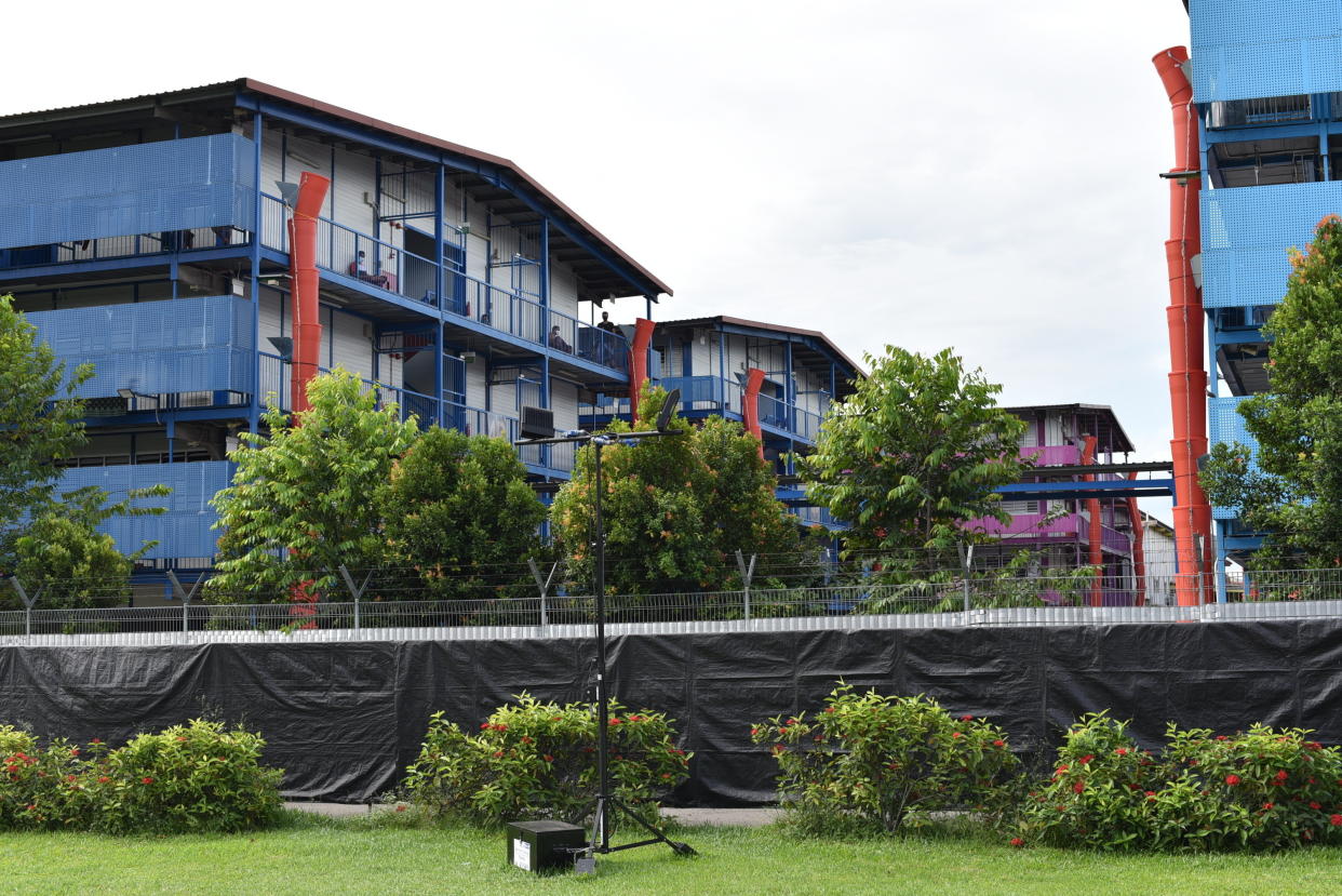 In this Sunday, May 10, 2020, photo, people sit outside a building balcony at the S11@Punggol, a complex of dormitory buildings for foreign workers in Singapore. A second wave of coronavirus infections in tightly packed foreign workers' dormitories has caught Singapore off guard, and exposed the danger of overlooking marginal groups in a health crisis. (AP Photo/YK Chan)