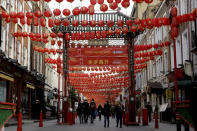 People walk beneath lanterns hung across the street to celebrate the Chinese Lunar New Year which marks the Year of the Ox, in the Chinatown district of central London, Friday, Feb. 12, 2021. Chinese New Year celebrations were muted in London as England remains in its third national lockdown since the coronavirus outbreak began. (AP Photo/Matt Dunham)