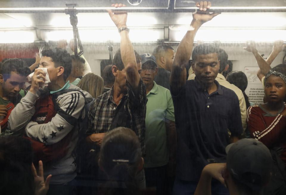 A man covers his face with a handkerchief while riding on the subway in Caracas, Venezuela, Friday, March 13, 2020. Venezuela's Vice President Delcy Rodríguez confirmed Friday the first two cases of the new coronavirus in the South American country. The vast majority of people recover from the new virus. (AP Photo/Ariana Cubillos)