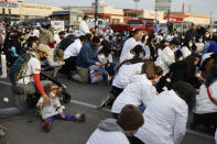 A kid sits on the road as other demonstrators take a knee during a peace walk honoring the life of police shooting victim 13-year-old Adam Toledo, Sunday, April 18, 2021, in Chicago's Little Village neighborhood. (AP Photo/Shafkat Anowar)