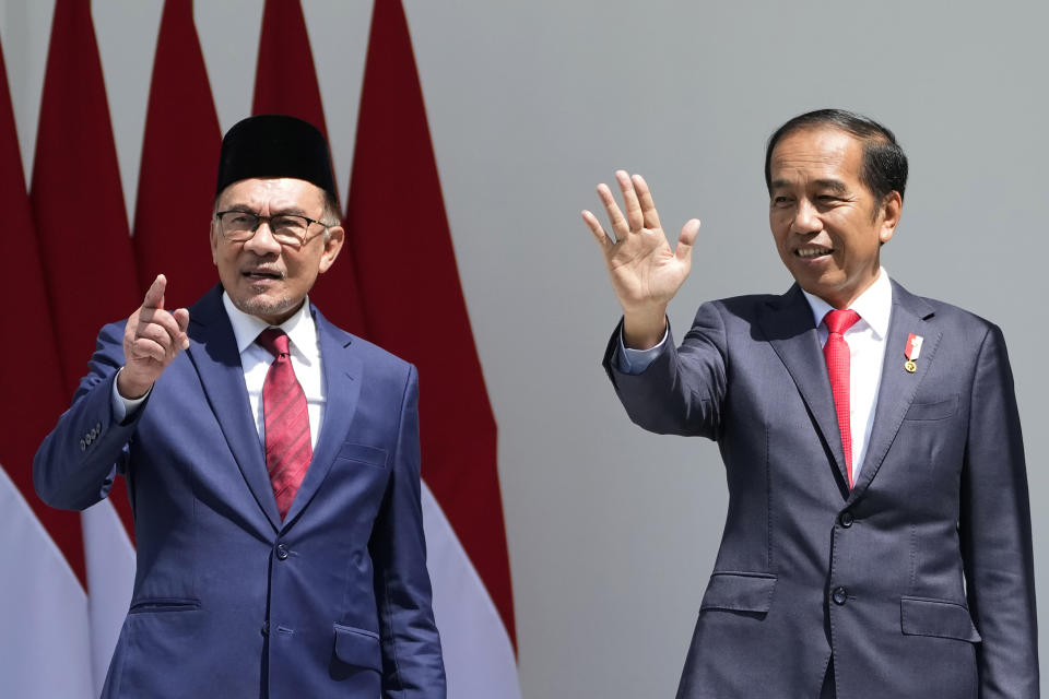 Indonesian President Joko Widodo, right, and Malaysia's Prime Minister Anwar Ibrahim wave at media during their meeting at the presidential palace in Bogor, West Java, Indonesia, Monday, Jan. 9, 2023. (AP Photo/Achmad Ibrahim)