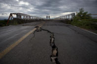 <p>Men walk across the bridge that connects Juchitan to Union Hidalgo in Oaxaca state, Mexico, Sunday, Sept. 10, 2017. While the bridge survived Thursday’s magnitude 8.1 earthquake, the road leading up to each side fissured and the supporting walls buckled. Wary of using the bridge, taxis are now waiting on either side to ferry passengers, who cross the bridge on foot. (AP Photo/Rebecca Blackwell) </p>