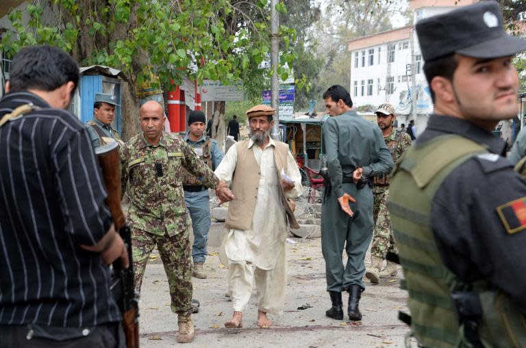 An Afghan security official assists an injured man following a suicide attack outside a bank in Jalalabad on April 18, 2015