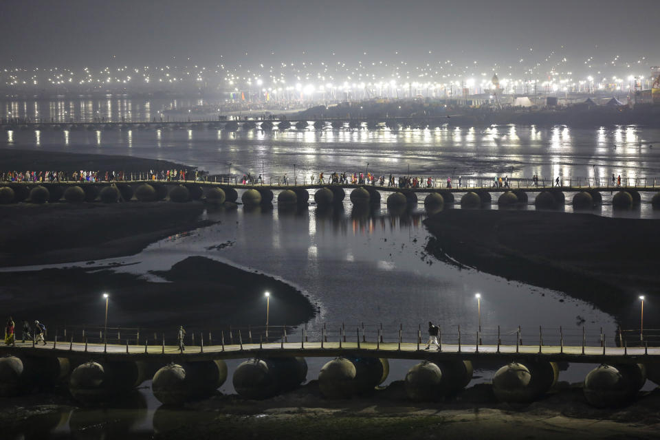 Indian Hindu pilgrims walk on a pontoon bridge before dawn at Sangam, the confluence of rivers Ganges, Yamuna, and mythical Saraswati during Magh Mela, a festival that attracts millions of pilgrims every year, in Prayagraj, in the northern Indian state of Uttar Pradesh, Thursday, Jan. 30, 2020. In the run-up to the bathing festivals, extra water is released upstream and tanneries are temporarily closed to temporarily clean up the waters of the Ganges. But pollution officials say that it is unsafe to bathe in the Ganges anywhere near Prayagraj. To Hindus, however, the river remains pure in a religious sense. (AP Photo/Altaf Qadri)