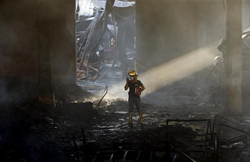 An arson investigator talks on a two-way radio inside a gutted slipper factory in Valenzuela