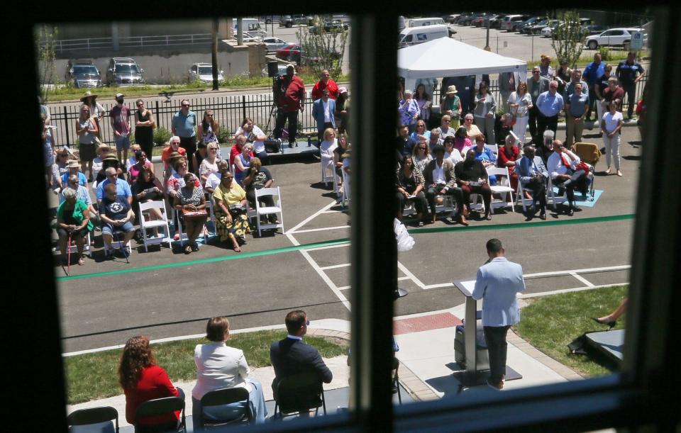 Pictured through an upstairs window, Patrick Bravo, executive director of The Summit County Land Bank, speaks at the ribbon-cutting ceremony of its new offices at the former home of John S. Knight in Akron on Friday.