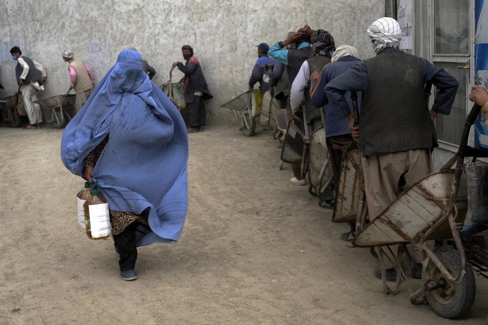 FILE - An Afghan woman receives a food ration distributed by a South Korean humanitarian aid group, in Kabul, Afghanistan, May 10, 2022. (AP Photo/Ebrahim Noroozi, File)