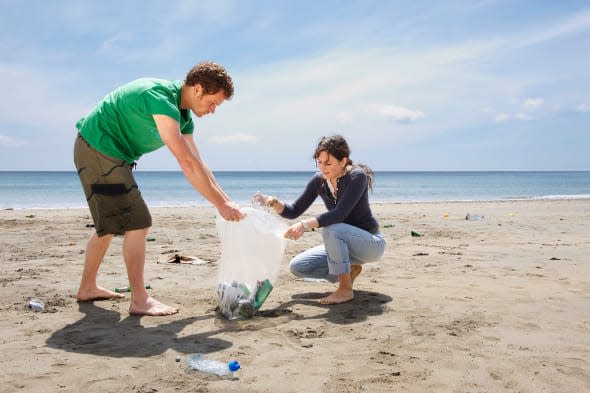 B4WW7R Young couple collecting garbage on beach