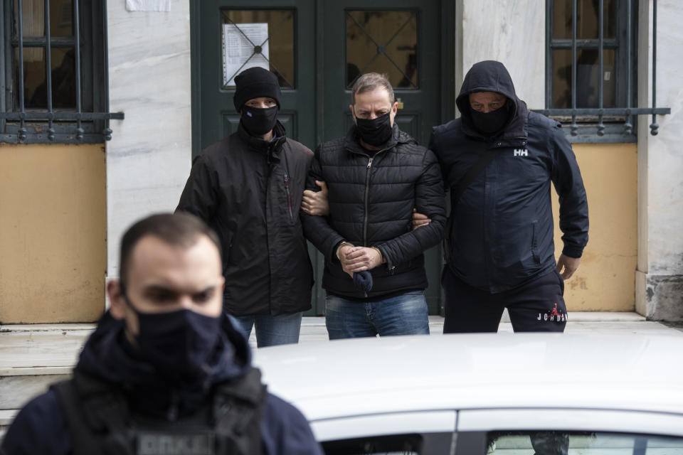 Plain clothed police officers escort handcuffed well-known actor and director Dimitris Lignadis, center, as they leave a magistrate's office in Athens, Sunday, Feb. 21, 2021. Lignadis, 56, the former artistic director of Greece's National Theatre, has been arrested on rape charges, police say. (AP Photo/Yorgos Karahalis)