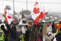 Protesters and supporters against a COVID-19 vaccine mandate for cross-border truckers cheer as a parade of trucks and vehicles pass through Kakabeka Falls outside of Thunder Bay, Ontario, on Wednesday, Jan. 26, 2022. (David Jackson/The Canadian Press via AP)