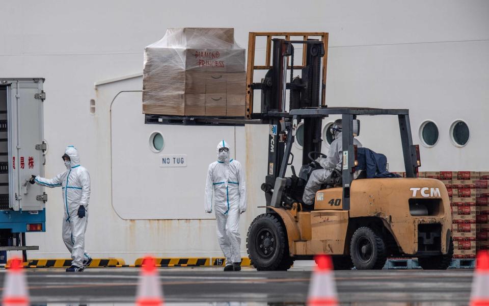 Workers in protective clothing load Amazon parcels on to Diamond Princess - Getty