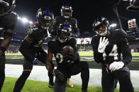 Baltimore Ravens outside linebacker Odafe Oweh, center, holds the ball while posing for photos with cornerback Anthony Averett (23), outside linebacker Tyus Bowser, top, and cornerback Marlon Humphrey (44) after recovering a fumble by Cleveland Browns quarterback Baker Mayfield during the first half of an NFL football game, Sunday, Nov. 28, 2021, in Baltimore. (AP Photo/Nick Wass)