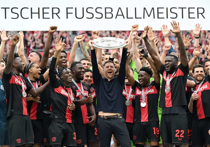 Bayer Leverkusen Coach Xabi Alonso (C) celebrates with the championship trophy following the German Bundesliga soccer match between Bayer Leverkusen and FC Augsburg at BayArena. Federico Gambarini/dpa