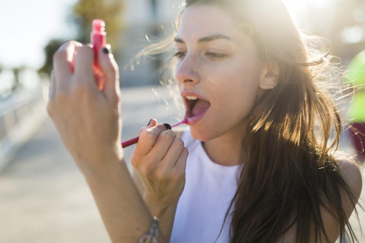 young woman applying lip gloss