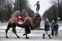 <p>Ein Junge reitet mit einem Kamel an einer Statue des russischen Kaisers Paul I. in Gattschina südlich von St. Petersburg vorbei. (Bild: AP Photo/Dmitri Lovetsky) </p>