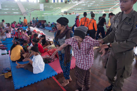 An evacuated villager from locations near the summit of Mount Agung, an active volcano which is showing increased seismic activity, is helped at a temporary shelter in Klungkung, on the resort island of Bali, Indonesia September 22, 2017 in this photo taken by Antara Foto. Antara Foto/Nyoman Budhiana/via REUTERS ATTENTION EDITORS - THIS IMAGE WAS PROVIDED BY A THIRD PARTY. MANDATORY CREDIT. INDONESIA OUT. NO COMMERCIAL OR EDITORIAL SALES IN INDONESIA.