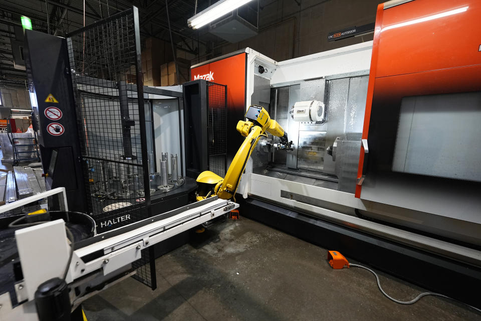 A Halter robot collects a finished piece for blood pressure pumps from a Mazak Integrex at Reata Engineering and Machine Works Thursday, Feb. 15, 2024, in Englewood, Colo. Reata, which supplies the aviation and medical device industries, has invested heavily in software that automates its manufacturing processes. It's also been training workers to use more sophisticated equipment. (AP Photo/David Zalubowski)