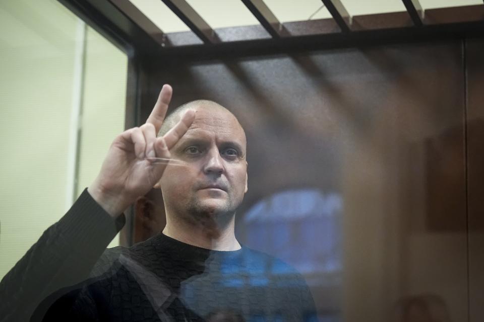Sergei Udaltsov, Russian left-wing political activist, gestures standing behind a glass in a cage in a courtroom in Moscow, Russia, Friday, Jan. 12, 2024. A Russian state news agency says a Russian court has ordered that a pro-war activist and critic of President Vladimir Putin be remanded into custody until Feb. 15. That's when Sergei Udaltsov will stand trial for charges of "justifying terrorism." (AP Photo/Alexander Zemlianichenko)