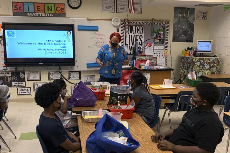 In this photo provided by Charlotte-Mecklenburg Schools, Kenza Haynes instructs in the science lab at Elizabeth Traditional Elementary school, part of Charlotte-Mecklenburg Schools' summer program, in Charlotte, NC, Monday, June 14, 2021. Across the country, school districts were able to greatly expand their summer offerings by leveraging federal pandemic relief funding. (Charlotte-Mecklenburg Schools via AP)