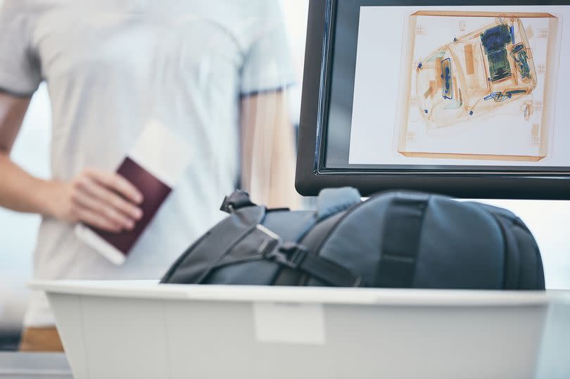 Airport security check. Young man holding passport and waiting for x-ray control his luggage.