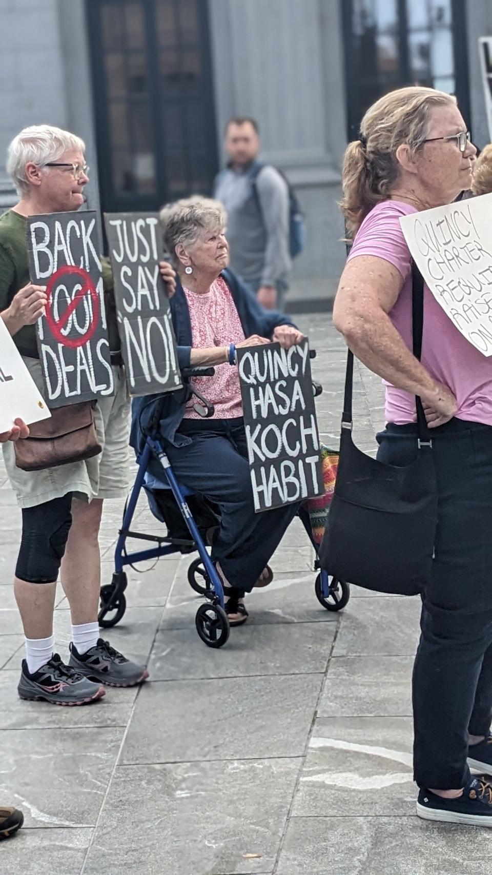 Protesters hold signs expressing their opposition to a large pay raise proposed for Mayor Thomas Koch on Wednesday, May 29, 2024.